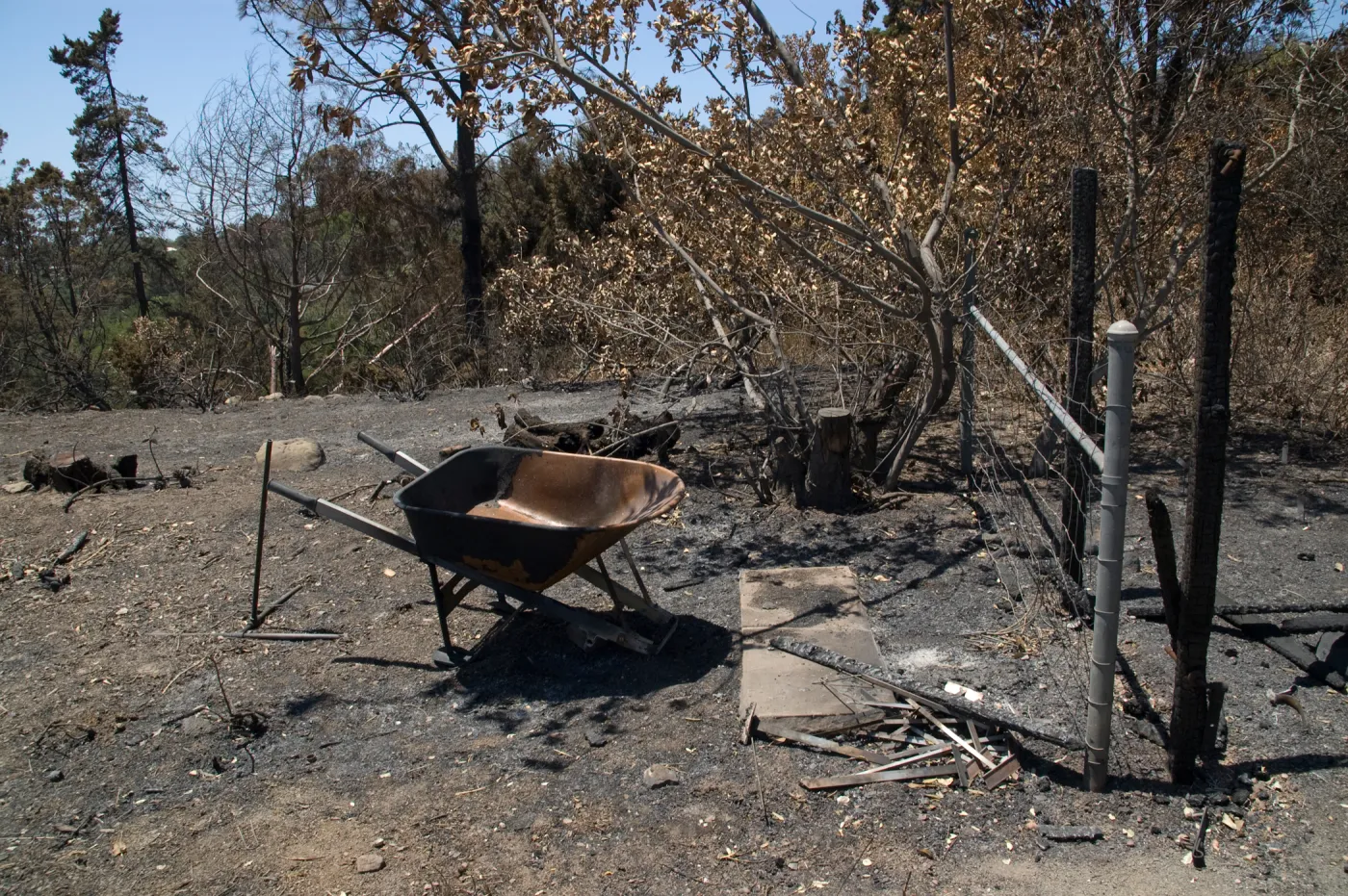 burned fence and gate, wheelbarrow, and tools after the Jesusita Fire