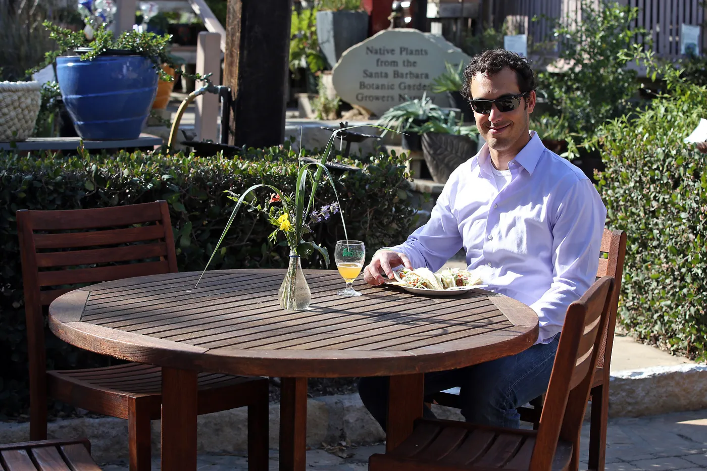 Santa Barbara Beer Garden Event, visitor seated at wood table in the Courtyard