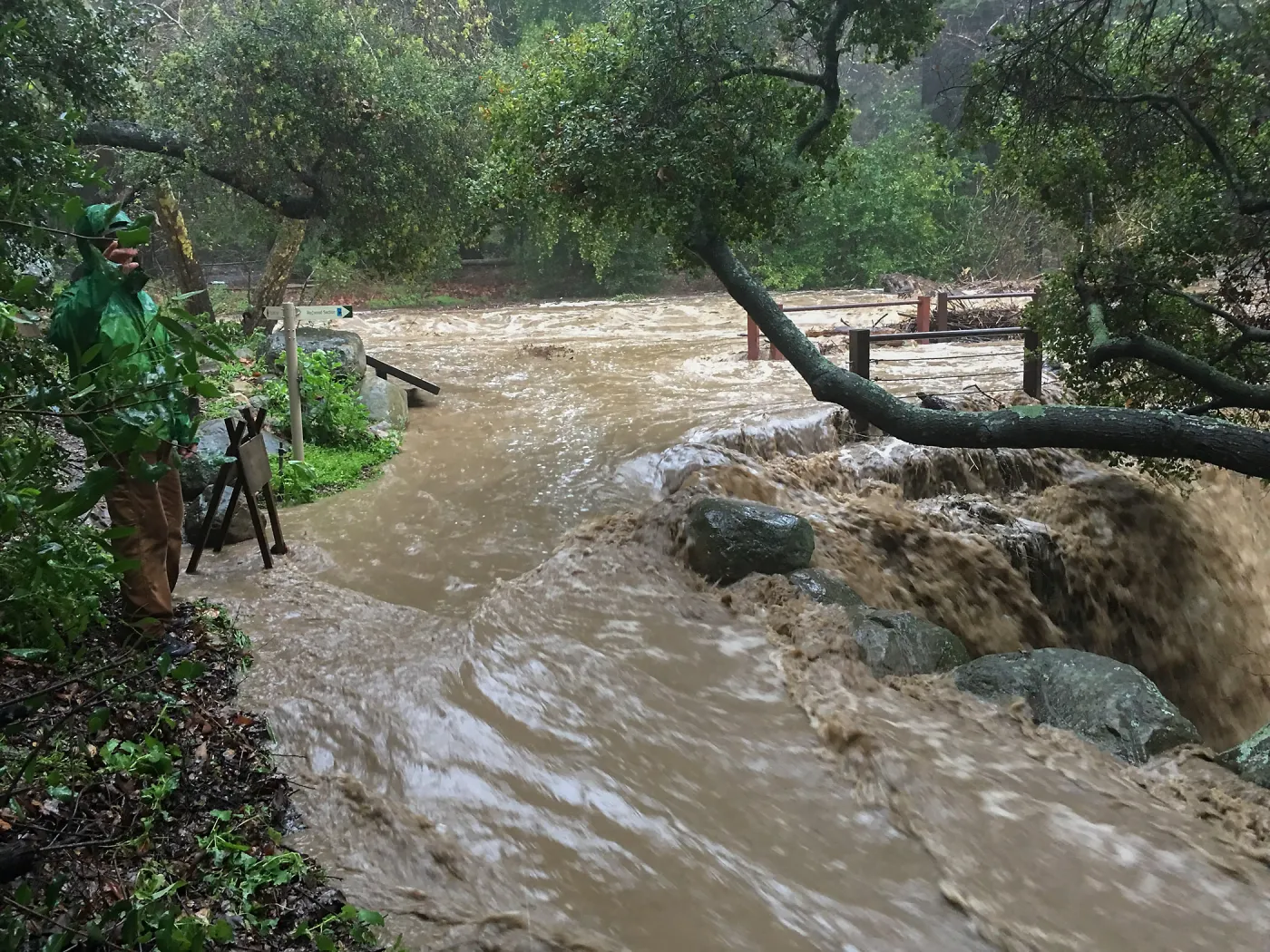 Water flowing around west end of Mission Dam during rainstorm