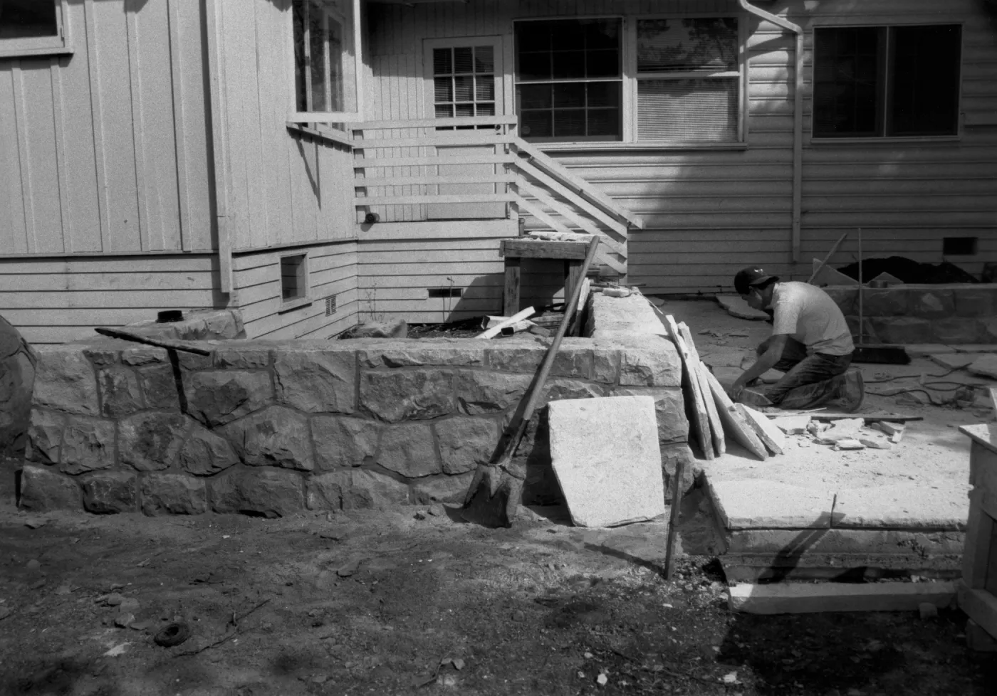Patio & stone walls under construction in the Home Demonstration Garden. Workman laying flagstone
