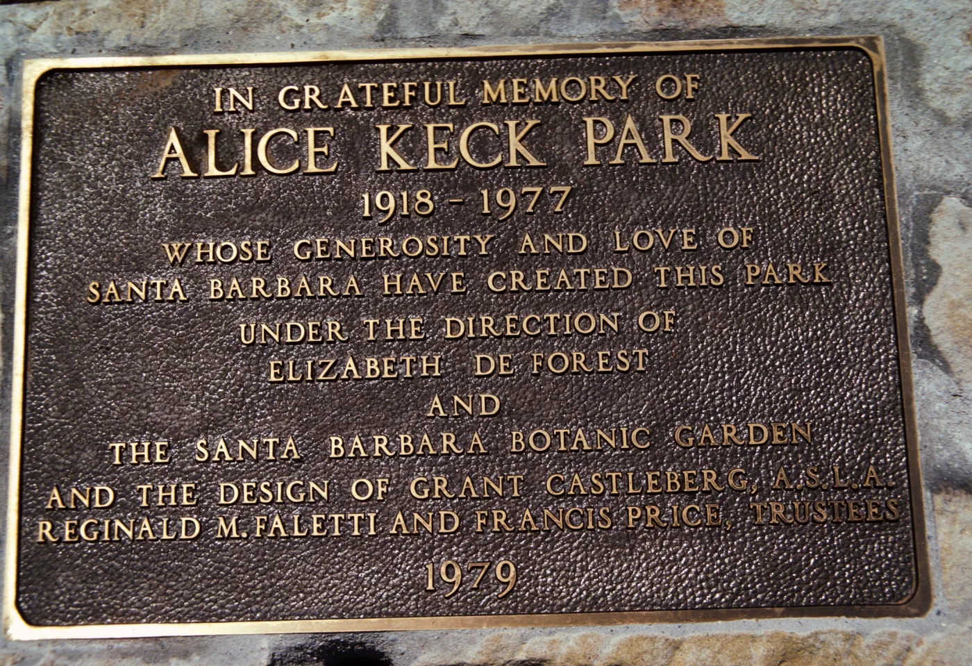 A brass-colored plaque that reads "In greateful memory of Alice Keck Park. 1918-1977, whose generosity and love of Santa Barbara have created this park under the direction of Elizabeth Forest and the Santa Barbara Botanical Garden and the design of Grant Castleburg A.S.L.A. Reginald M. Faletti and Francis Price, trustees, 1979."