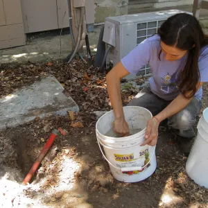 Betsy Lape setting new grid marker in concrete