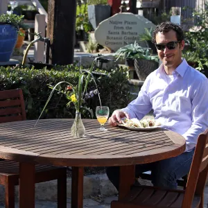 Santa Barbara Beer Garden Event, visitor seated at wood table in the Courtyard