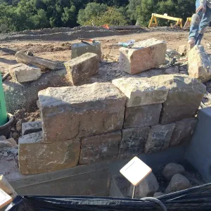 Construction of back wall of rill at Pritzlaff Conservation Center using cut stone from Gane house foundation