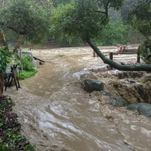Water flowing around west end of Mission Dam during rainstorm