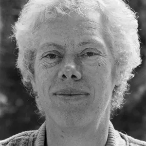 A black and white close up image of a smiling short haired older woman with the neck of her sweater showing.
