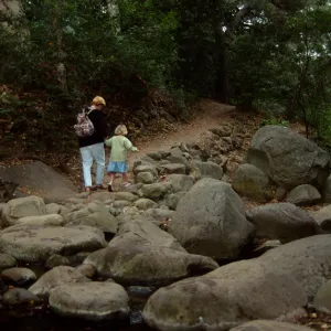 family crossing Mission Creek on boulders at creek crossing